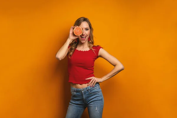 カラフルなオレンジの背景にグレープフルーツを保持する女性の肖像画 — ストック写真