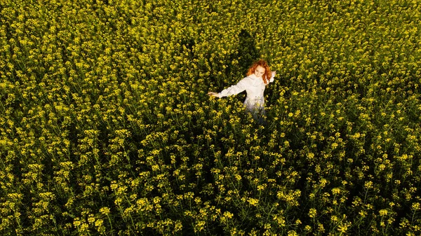 年轻的红头发女人在日落时在一片黄色的田野里画像 空中景观 — 图库照片