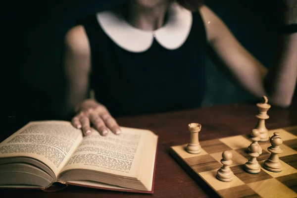 女人在黑暗背景下下下下棋和下棋 后期制作中添加了旧的电影效果 有选择地关注这本书 — 图库照片