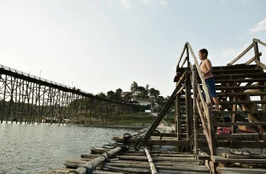 SANGKHLABURI-KANCHANABURI, THAILAND - 30 Mart 2015: Sangkhlaburi, Kanchanaburi, Tayland 'daki Wooden köprüsünden nehre atlayan bilinmeyen çocuk.