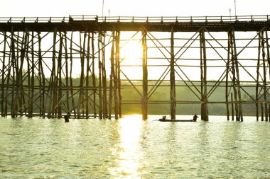 Sangkhlaburi Bölgesi, Kanchanaburi, Tayland 'da eski ahşap köprü (Mon Bridge) şoförüyle birlikte geleneksel uzun kuyruk teknesi.