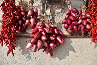  Görüntü, duvarda asılı duran ve güneşte kuruyan ünlü kırmızı soğan ve kırmızı biber demetlerini gösteriyor. Sahne, kırsal bölgelerde geleneksel yiyecek saklama ve saklama yöntemlerini yansıtıyor. Yüksek kalite fotoğraf