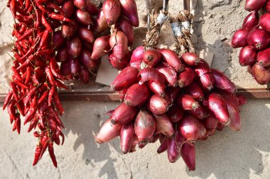Görüntü, duvarda asılı duran ve güneşte kuruyan ünlü kırmızı soğan ve kırmızı biber demetlerini gösteriyor. Sahne, kırsal bölgelerde geleneksel yiyecek saklama ve saklama yöntemlerini yansıtıyor.