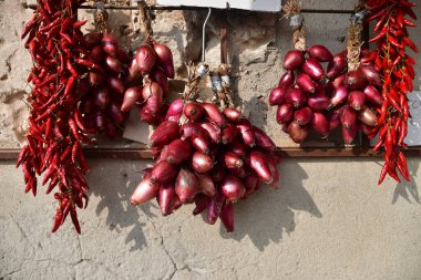 Görüntü, duvarda asılı duran ve güneşte kuruyan ünlü kırmızı soğan ve kırmızı biber demetlerini gösteriyor. Sahne, kırsal bölgelerde geleneksel yiyecek saklama ve saklama yöntemlerini yansıtıyor.