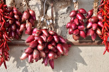 Görüntü, duvarda asılı duran ve güneşte kuruyan ünlü kırmızı soğan ve kırmızı biber demetlerini gösteriyor. Sahne, kırsal bölgelerde geleneksel yiyecek saklama ve saklama yöntemlerini yansıtıyor.