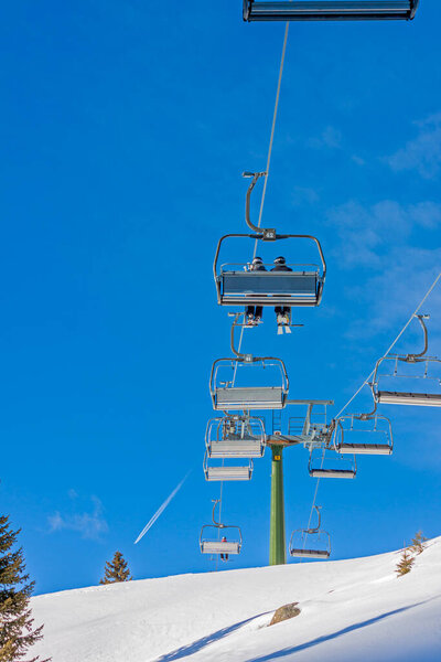 Chair lift with skiers at ski resort on a blue sky