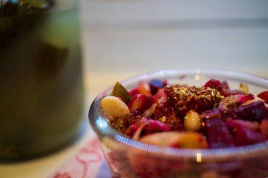 Vinaigrette with beans, dressed with seasonings. Jar of homemade pickles on the background