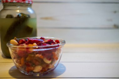 Vinaigrette with beans, dressed with seasonings. Jar of homemade pickles on the background