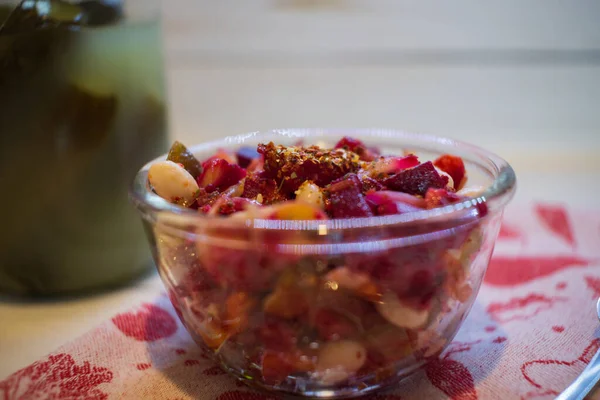 Vinaigrette with beans, dressed with seasonings. Jar of homemade pickles on the background