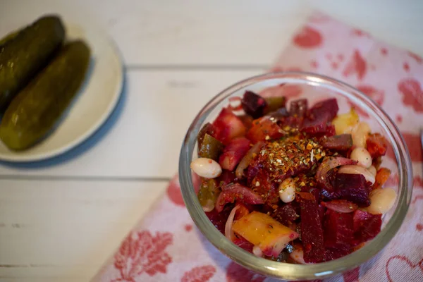 Vinaigrette in the glass bowl on the fabric napkin. Plate with pickles on the background.
