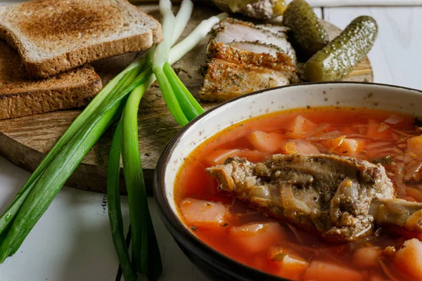 stock image Homemade ukrainian borsch - beetroot soup in a bowl. Green onion, bread, bacon with herbs and pickles 