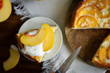 Üstünde krema ve şeftali olan bir parça cheesecake.. 