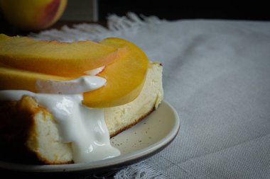 Üstünde krema ve şeftali olan bir parça cheesecake.. 