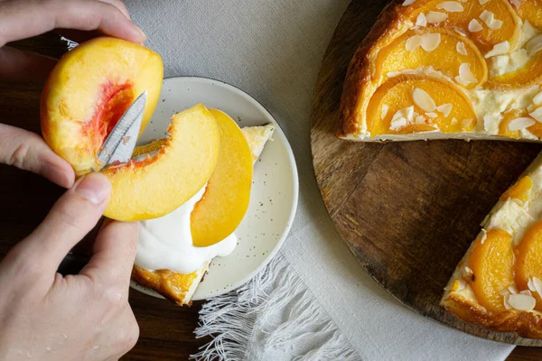 Woman putting piece of peach on the top of the cheesecake