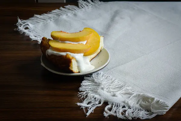 A piece of cheesecake with sour cream and peaches on the top.