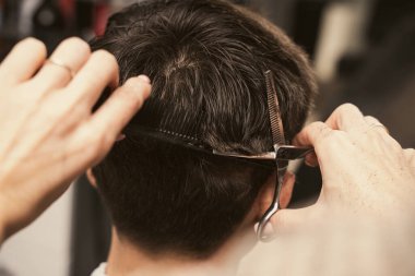 Genç adam modern bir saç kesimi yaptırıyor. Kız kuaför bir adamı makasla keser. Erkek modası ve tarzı. Saç bakımı, güzellik endüstrisi, berber konsepti. Berber dükkanındaki adamlar saç stili..