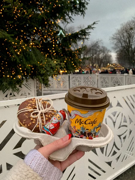 christmas decoration, hand with a cup of tea or coffee and a donut and candy in front of the christmas tree