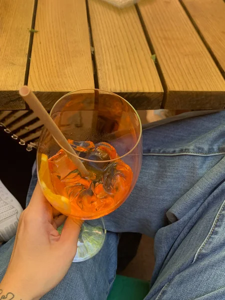 Elinde bir bardak portakal suyu ya da apperol spreyi olan bir kadın.