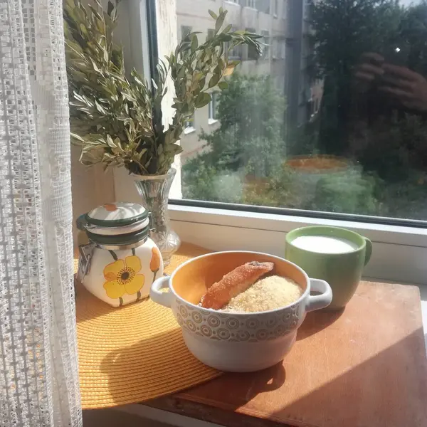 Güneşli havada, pencerenin yanında süt ve kurabiyeli kahvaltı.
