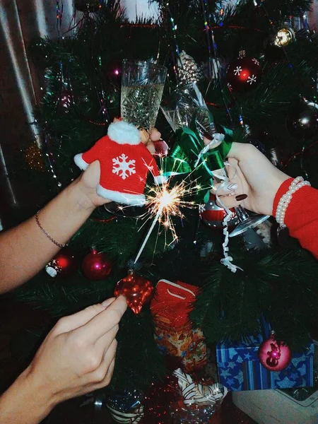 Sıcak kış ayrıntıları, elinde Noel eşyaları, şampanyalı gözlük ve şömineli bir kız.