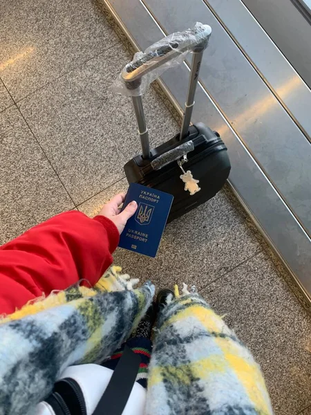 girl holding Ukrainian passport with a suitcase in the airport
