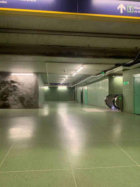 interior design of an empty underground parking lot or underground subway, layout of a spacious place with green color tiles and switched on lamps 