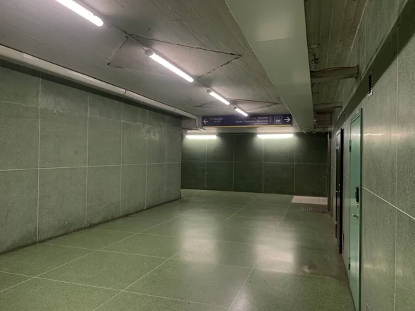 interior design of an empty underground parking lot or underground subway, layout of a spacious place with green color tiles and switched on lamps 