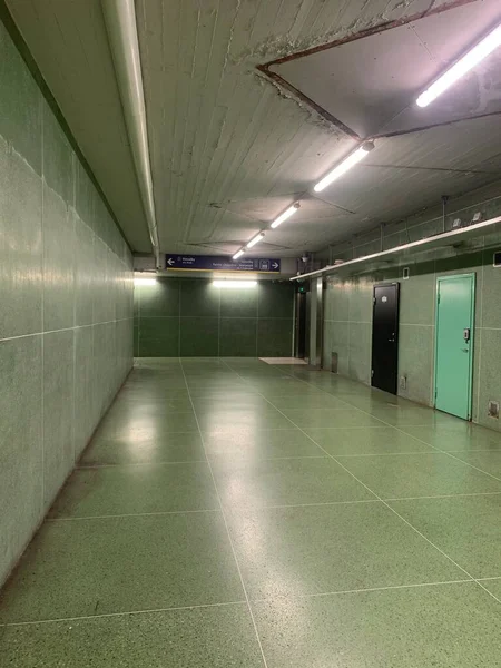interior design of an empty underground parking lot or underground subway, layout of a spacious place with green color tiles and switched on lamps 