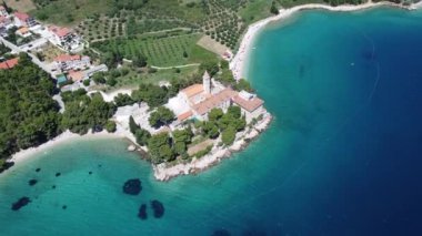 Drone view of Martinica beach in Bol on Brac Island, Croatia. Tourists enjoying summer vacation in Europe. Croatian attraction on Mediterranean Sea, with old monastery, church and people swimming