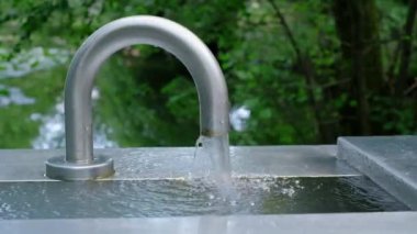 Yeşil arka planda duran bir musluk suyu. Açık havada akan bir suya yaklaş. Ağır çekim video, tam HD. 