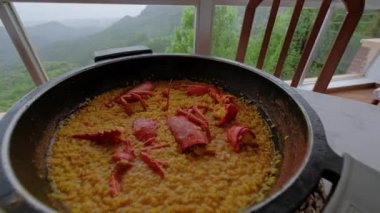 Geleneksel İspanyol yemeği. Istakozlu Paella. Valencia 'dan lezzetli yemekler. Arka planda dağlar olan güzel bir manzara. Yavaş çekim videosu. 