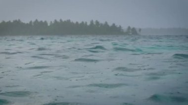 Maldivler 'de yağmurlu bir gün. Güzel bir turkuaz renk denizine su damlaları yakın. Dalgaların yavaş hareketi. Islak mevsim. Fırtınalı hava. 4k video.