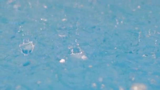 ヘイルでスローモーションビデオ 冷凍液滴 ドロップを閉じます 青いスイミングプールの水面に雨 雹の石の落下から大きな飛沫 水平ビデオ — ストック動画