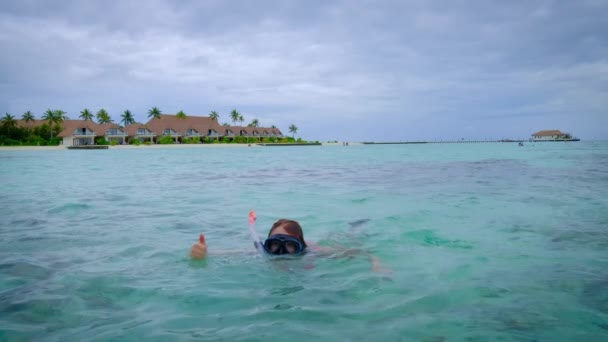 赤いビキニの女がシュノーケリングをしている モルディブで幸せ 背景に青いターコイズブルーの海 女の子は熱帯の休日を楽しんでいます 夏の旅行休暇のコンセプト — ストック動画