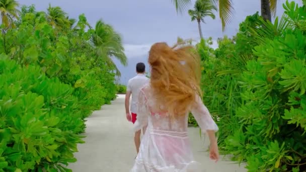 男人在走路 女人在他的背上跳 一对夫妇在度假 对马尔代夫感到高兴 绿色的热带植物为背景 暑假的概念 慢动作4K视频 — 图库视频影像