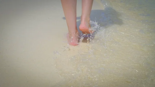 モルディブのエキゾチックな白い砂浜を歩く女性のクローズアップ 澄んだ水の水しぶきと波 夏の旅行休暇のコンセプト — ストック写真