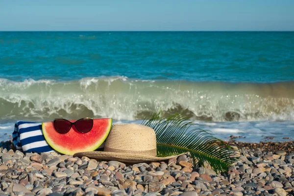 Kamienistej Plaży Leży Kapelusz Okulary Przeciwsłoneczne Arbuz Liść Tropikalny Ręcznik — Zdjęcie stockowe