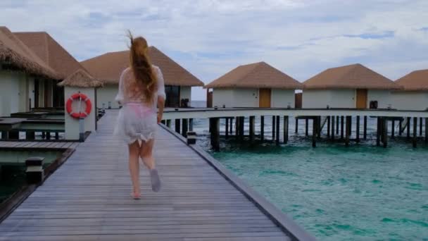 穿着比基尼的女人在跑步 女性在马尔代夫很快乐 蓝色蓝绿色的海洋为背景 女孩喜欢她的热带假期 暑假的概念 慢动作全息高清视频 — 图库视频影像
