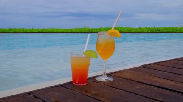 スイミングプール付きのカクテルを閉じます 飲み物が２杯立っている 背景に青いターコイズブルーの海 夏の旅行休暇のコンセプト 4Kスローモーションビデオ — ストック動画