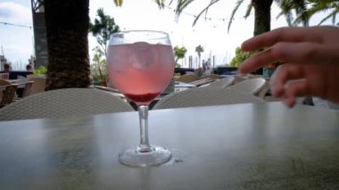 Pembe su ve buz küplü cin tonik. Arka planda güzel avuçlar var. Yaz tatili havası. Tam HD yavaş çekim videosu. 