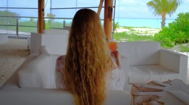 Cep telefonu ve kokteyli olan bir kadın. Maldivler 'de mutlu bir kadın. İçkinin fotoğrafını çeken bir kız. Arka planda mavi turkuaz okyanus. Kız tropikal tatillerin tadını çıkarıyor. Yaz tatili