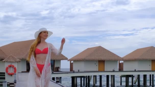 穿着比基尼的女人在走路 女性在马尔代夫很快乐 蓝色蓝绿色的海洋为背景 女孩喜欢她的热带假期 暑假的概念 慢动作全息高清视频 — 图库视频影像
