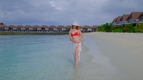 穿着比基尼的女人在走路 女性在马尔代夫很快乐 蓝色蓝绿色的海洋为背景 女孩喜欢她的热带假期 暑假的概念 慢动作4K视频 — 图库视频影像