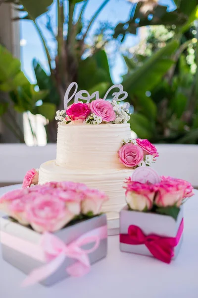Wedding cake decorated with rose flowers. Picture for a menu or a confectionery catalog. Close up of a white cake with love letters. High quality photo.
