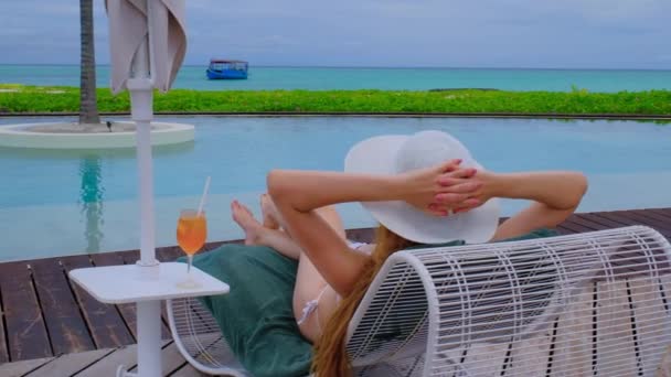 穿着比基尼配鸡尾酒的女人在睡觉 马尔代夫的快乐女性 蓝色蓝绿色的海洋为背景 女孩喜欢她的热带假期 暑假的概念 慢动作4K视频 — 图库视频影像