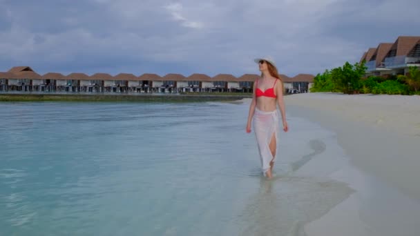 穿着比基尼的女人在走路 女性在马尔代夫很快乐 蓝色蓝绿色的海洋为背景 女孩喜欢她的热带假期 暑假的概念 慢动作4K视频 — 图库视频影像