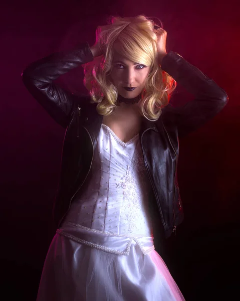 Scary woman in a wedding dress and a leather jacket. Blonde creepy girl on a red background with a fog. Happy Halloween concept. Dark evil female.