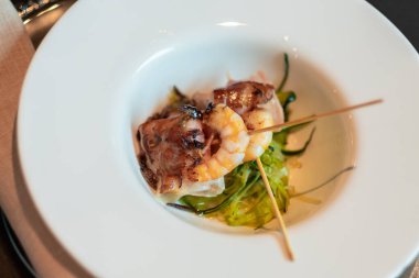 Shrimps with bacon in white plate. Close-up of a tasty food. Small snack. 