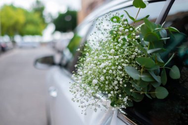 Close up of luxury wedding car flowers decoration. Nuptial event. Beautiful gypsophila white green flowers.