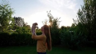 Woman holding a small cute Chihuahua puppy at sunset. Long-haired pet miniature dog with brown hair. Adorable little friend. Companion friendly dog. Funny purebred canine. Slow motion. 